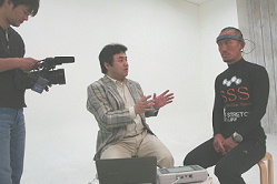 ストレッチ教材ビデオの撮影で兼子ただし氏の脳波を測定する和田知浩。